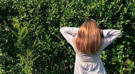 Portrait image of a young girl in a white blouse, with long hair in a summer gardenの写真素材