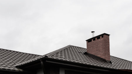 A fragment of a private new house with a fence and a roof in winter