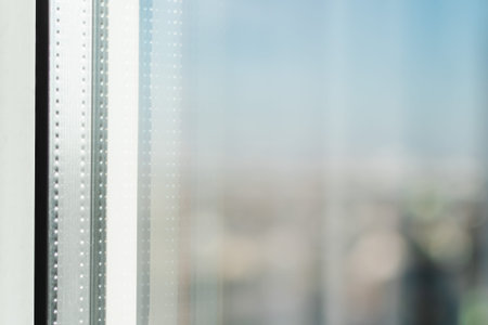 A fragment of a plastic window frame against the backdrop of an urban landscape and the sky