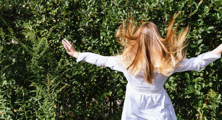Portrait image of a young girl in a white blouse, with long hair in a summer garden