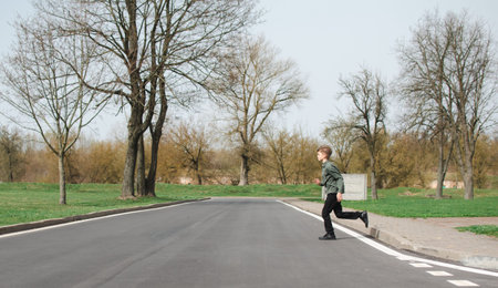 A little boy runs across the road for carsの写真素材