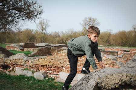 A little boy walks in the park near an old fortress with ruined wallsの写真素材
