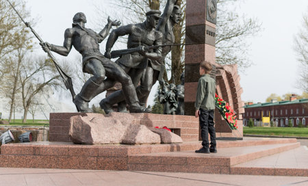 A little boy walks in the Brest fortress near the monument to soldiers