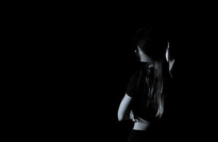 Creative image of a girl with a bow in the dark with one light sourceの写真素材
