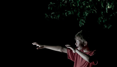 Creative image of a boy in the dark on the street with one light sourceの写真素材