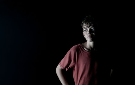 Creative image of a boy in the dark on the street with one light sourceの写真素材