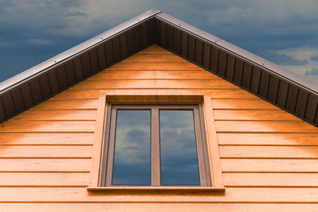 A fragment of a restored old village house with new windows and roofの写真素材