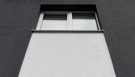 A fragment of a new private plastered house with white windows