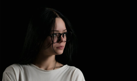 Portrait image of a young girl with glasses in the dark