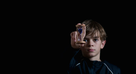 Portrait image of a boy with an hourglass on a dark backgroundの写真素材