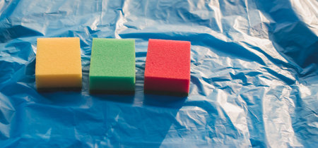 Sponges for washing dishes of different colors on a colored backgroundの写真素材