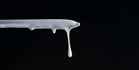 Dripping white thick paint on a dark backgroundの写真素材