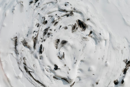 Streaks and drops of thick black paint on a light background