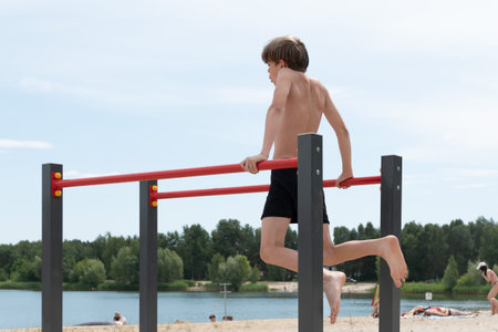 A little boy is engaged in gymnastics equipment, outdoors near a pond