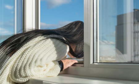 A young girl poses near a window in a multi-storey building