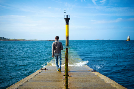 man walking to a lighthouse into the seaの写真素材
