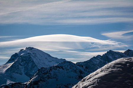 Winter mountain landscape with lenticular cloud. Italian Alps