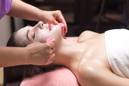 Beautiful woman with facial mask at beauty salon. hand with brushの写真素材