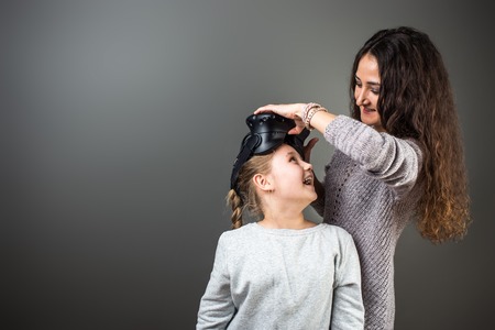 Mother and child playing together with virtual reality headsets indoors at homeの写真素材