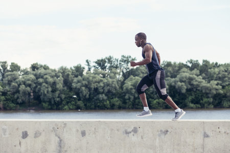 Healthy young athletic man running at the road