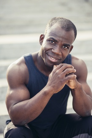 Portrait of attractive African athlete coming home after workout at fitness club, messaging via social networks. Healthy lifestyle conceptの写真素材