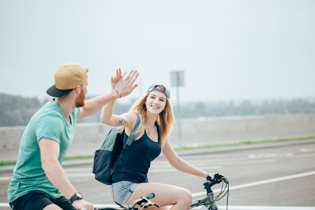 Fit cyclist couple standing at the summit high fiving on a sunny dayの写真素材