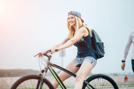Side view portrait of a young beautiful woman riding on bicycle in city streetの写真素材