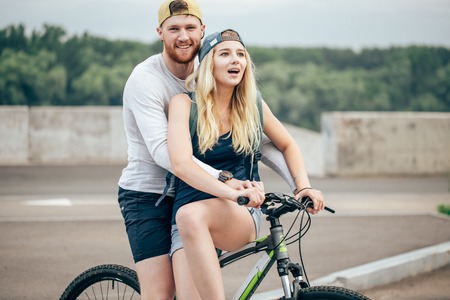 Happy man giving girlfriend a lift on his crossbar of bike on the beach.の写真素材