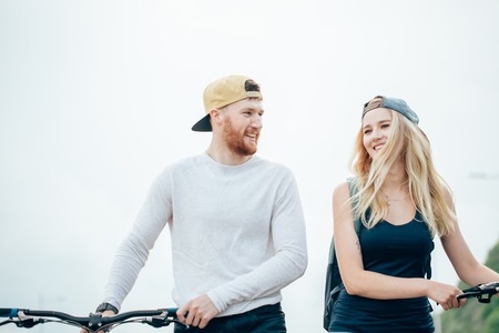 couple walking bikes together on road to stunning sunset with lens flareの写真素材