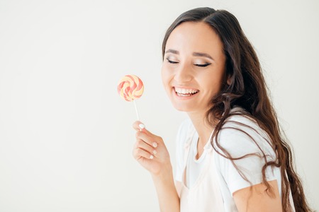 Cute young woman looking into the camera and holding a lollipop. Positive human emotions.の写真素材