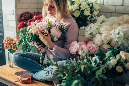 Florist shop in daylight. Woman holding beautiful bouquet of flowers. Florist with her work. Stylized tender photo with hipster filter.の写真素材
