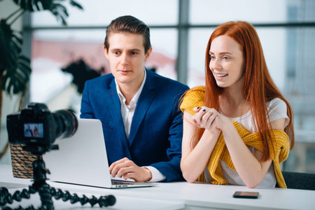 two video blogger talk about something and smiling.