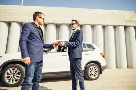 car sales. one person sells car and gives the key to the new owner