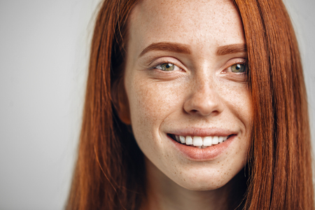 Headshot Portrait of happy ginger girl with freckles smiling looking at cameraの写真素材