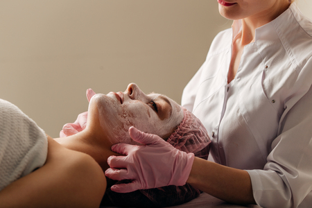 Beautician makes cleansing and exfoliating facial for beautiful girlの写真素材