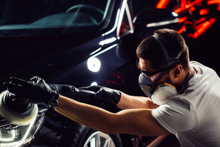 Car detailing - man with orbital polisher in auto repair shop. Selective focus.の写真素材