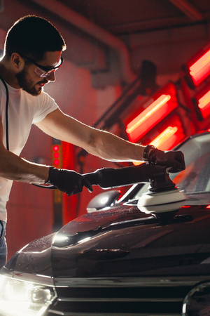 Car detailing - man with orbital polisher in auto repair shop. Selective focus.の写真素材