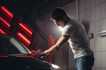 Car detailing - the man holds the microfiber in hand and polishes the carの写真素材