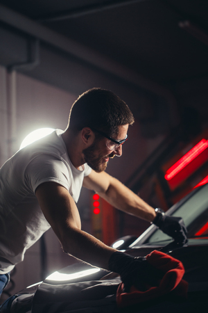 Car detailing - the man holds the microfiber in hand and polishes the carの写真素材