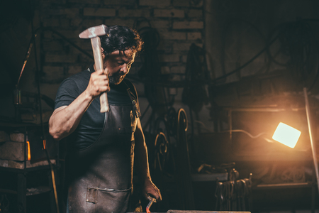 Blacksmith forging molten metal on the anvil in smithy.の写真素材