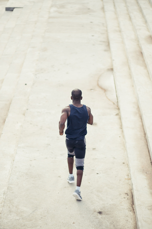 Rear view african american man running on the beachの写真素材