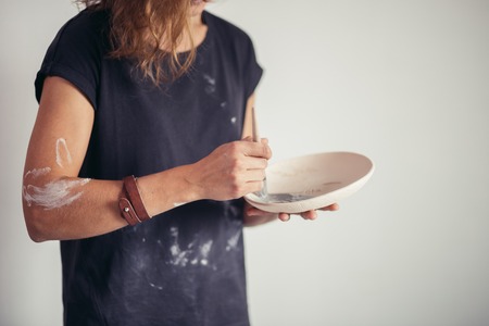 Woman painting clay pot with senior potter at workshopの写真素材
