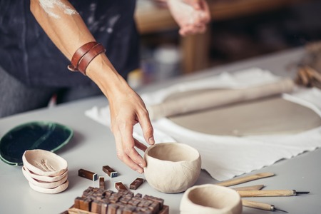 close-up hands of a Potter make a bowl from clayの写真素材