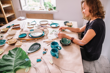 potter woman paints ceramic cup. Woman working In her pottery studioの写真素材