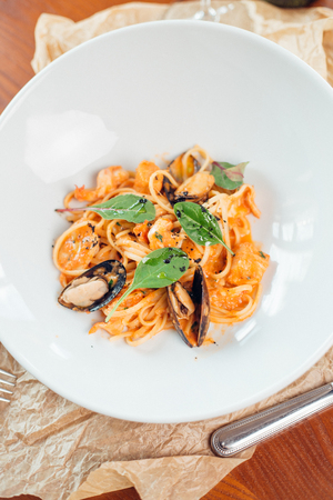Seafood Pasta with mussels and basil in white plate on wooden table.の写真素材