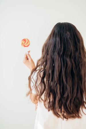 Beautiful sexy woman model with pink lips and lollipop on white backgroundの写真素材