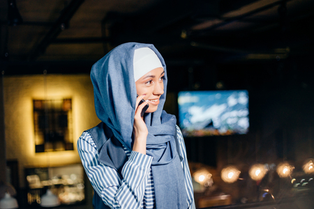 Muslim Woman On Break Using Mobile Phone In cafeの写真素材