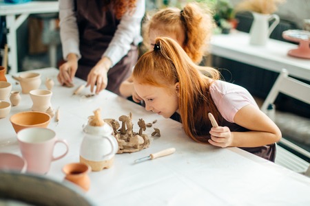 redhead mother and two daughter mold with clay, pottery childrenの写真素材