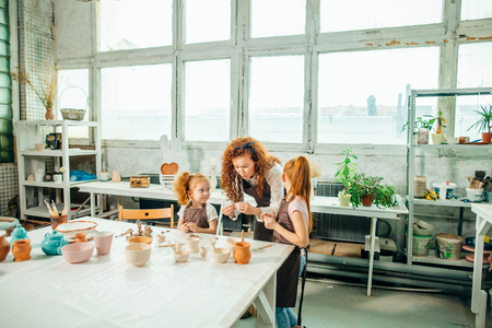 redhead Mother and kid daughter at home molded from clay and play togetherの写真素材