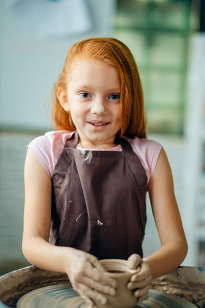 redhead Child sculpts from clay pot. workshop on modeling on potters wheel.の写真素材